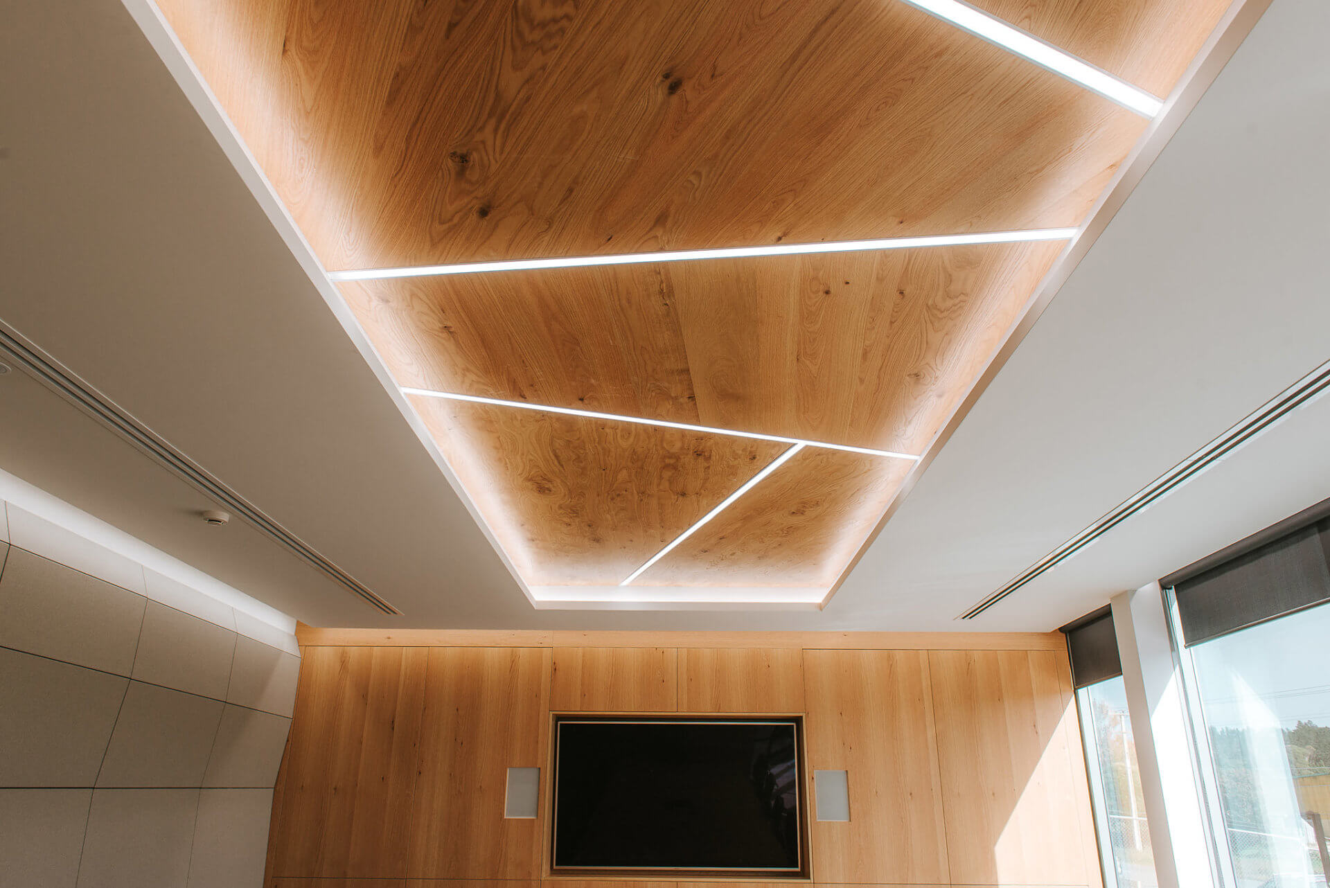 Oak veneer ceiling panels with recessed strip lighting.